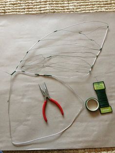 scissors, tape, and wire are laid out on a piece of paper to make a leaf craft