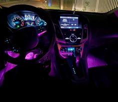 the interior of a car is lit up with purple lights and features electronic dashboard controls