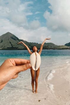 a person holding up a white ball on the beach