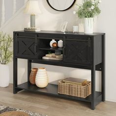 a black console table with baskets and vases on the bottom shelf next to it