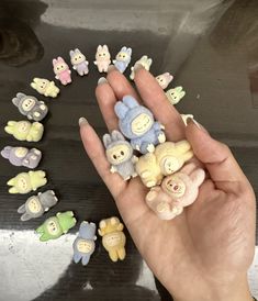 a hand holding several small stuffed animals in it's palm, surrounded by smaller ones