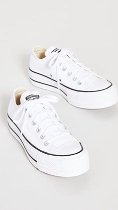 pair of white sneakers with black laces on them