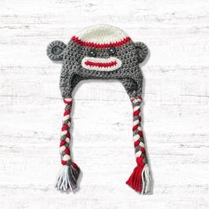 a crocheted hat with a sock monkey on the front and red, white, and gray stripes