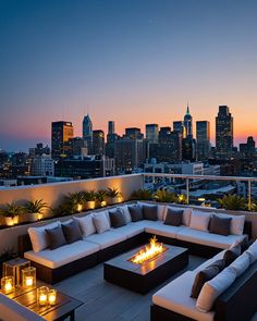 an outdoor fire pit on top of a roof with city skyline in the background at dusk