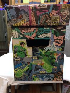 a cardboard box with comic covers on it sitting on top of a white cloth covered table