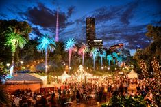 an outdoor event with palm trees and lights in the background at night time, surrounded by tall buildings