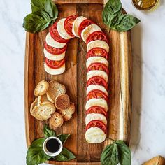 sliced tomatoes, mozzarella and basil on a wooden platter with garlic bread