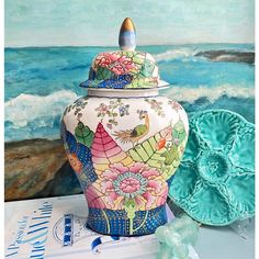 a vase sitting on top of a table next to a blue plate and some seashells