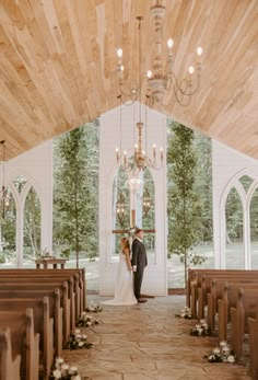 a bride and groom standing in front of the alter at their wedding ceremony with chandeliers hanging from the ceiling