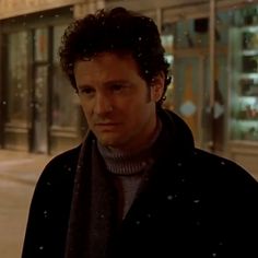 a man standing in front of a building on a street corner with snow falling all around him