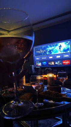 a glass of wine sitting on top of a table in front of a flat screen tv