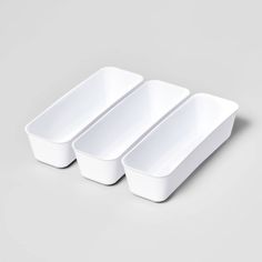 three white dishes sitting next to each other on a gray surface with no one in it