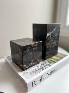 two black marble cubes sitting on top of a white table next to each other