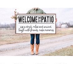 a man holding a sign that reads welcome to the patio, and there is no image on it