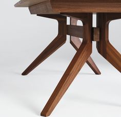 a close up of a wooden table with two intersecting legs and a square top, on a white background