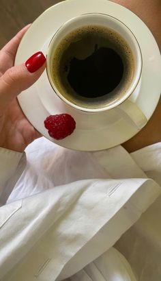 a woman holding a cup of coffee with raspberries on it