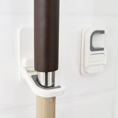 a close up of a door handle on a white wall with a brown pole attached to it