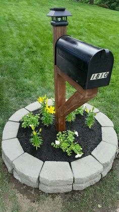 a mailbox in the middle of a flower bed