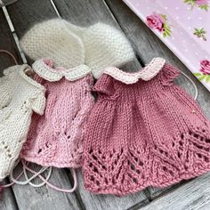 three knitted sweaters and hats sitting on top of a wooden table