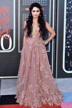 a woman in a pink dress standing on a red carpet with her hands on her hips