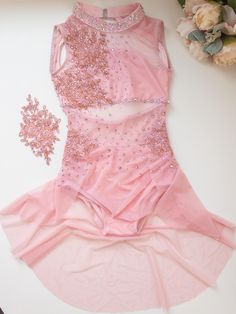 a pink leotard with sequins on it and a flower in the background