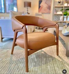 a tan leather chair sitting on top of a carpeted floor next to a lamp