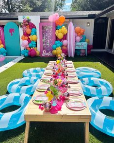 a table set up with balloons and plates for a birthday party in the backyard on grass