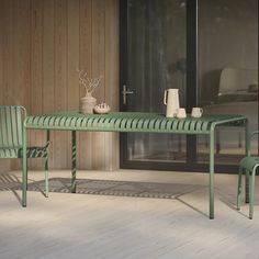 a green table and two chairs on a wooden floor next to a sliding glass door