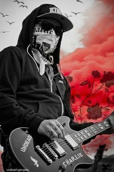 a man with face paint playing an electric guitar in front of a red and black background