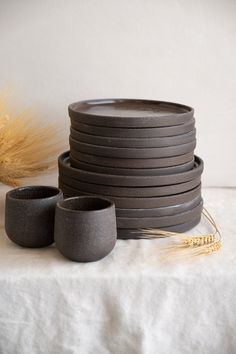 a stack of gray cups sitting on top of a table next to some wheat stalks