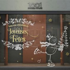 a store front window with christmas decorations on the glass and snowflakes around it