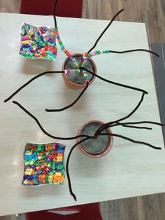 two small pots with beads on them sitting on top of a wooden table next to each other