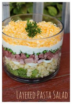 a layered salad in a glass bowl on a wooden table