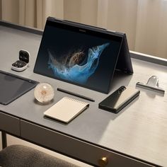 an open laptop computer sitting on top of a desk next to a phone and other items