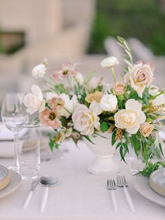 a white vase filled with lots of flowers sitting on top of a dining room table