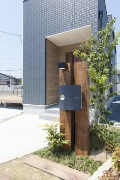 a wooden post with an electronic device attached to it in front of a blue building