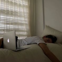 a woman laying in bed with an apple laptop