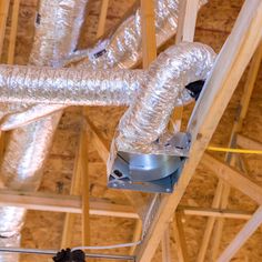 a man working on the ceiling in a building under construction with exposed pipes and duct tape