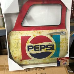 an old pepsi bottle in a cardboard box with the lid open to reveal it's logo