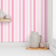 a pink and white striped wallpaper in a kitchen with two cups on the counter