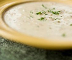 a yellow bowl filled with white sauce and garnished with parsley