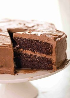 a chocolate cake with one slice taken out of it on a white cake platter