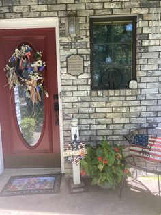 a red door with a wreath on it next to a chair and potted plant