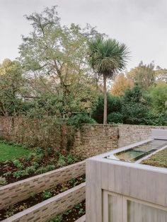 an outdoor garden with grass and trees in the background, surrounded by brick walling