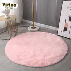 a round pink rug on the floor next to a table with pictures and a lamp