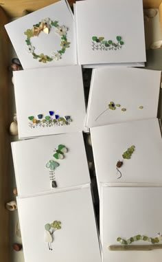 six cards with flowers and leaves on them are in a box next to some seashells