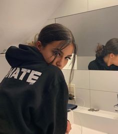 a girl is looking at her reflection in the mirror