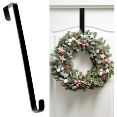 a christmas wreath hanging on the front door with a pair of black clothes pins next to it