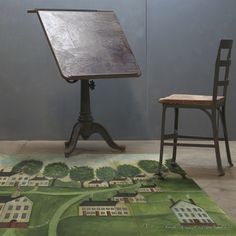 an old desk and chair with a painting on the floor next to it in front of a blue wall