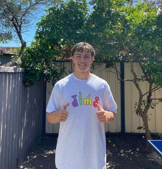 a young man standing in his backyard giving the thumbs up